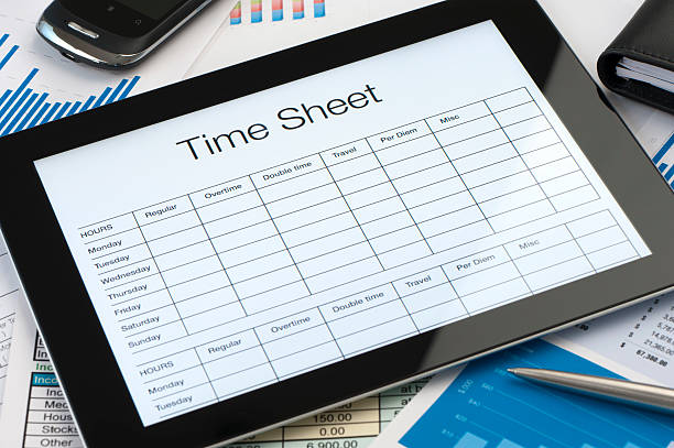 Online timesheet form on a digital tablet with paperwork